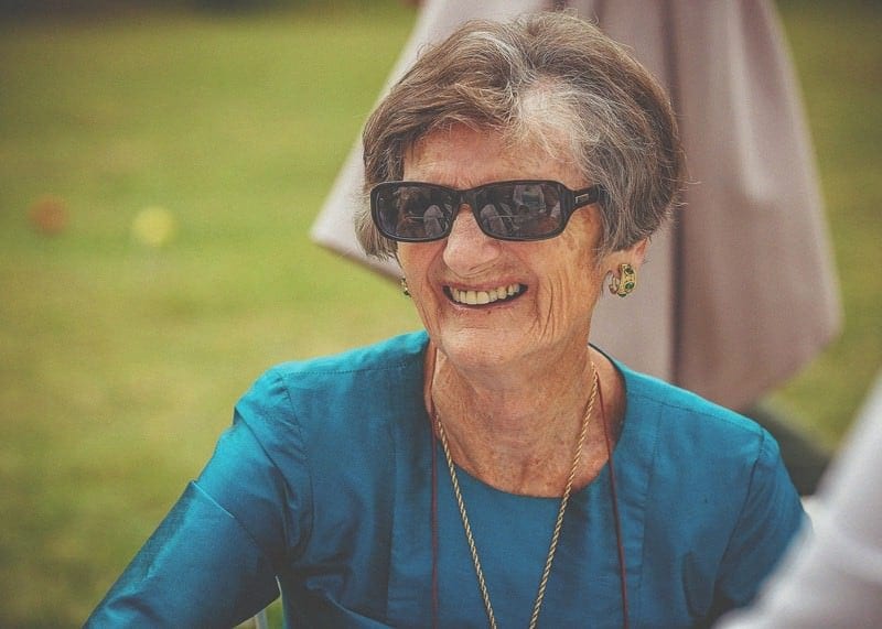 A lady with sunglasses on smiles outside at Almonry Barn