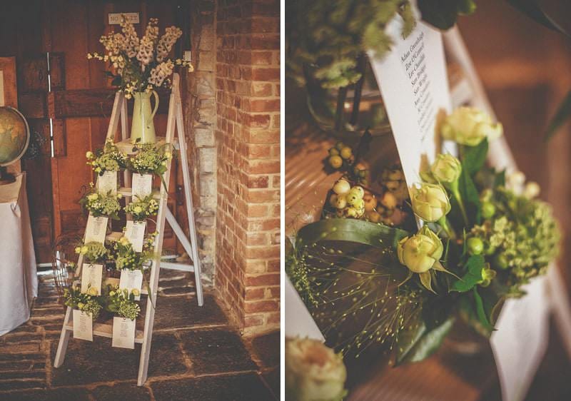 A wodden ladder in the corner of the barn with flowers on the steps