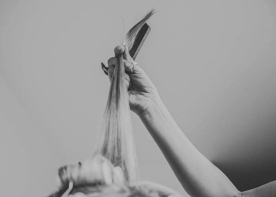 The make up artist holds the brides hair