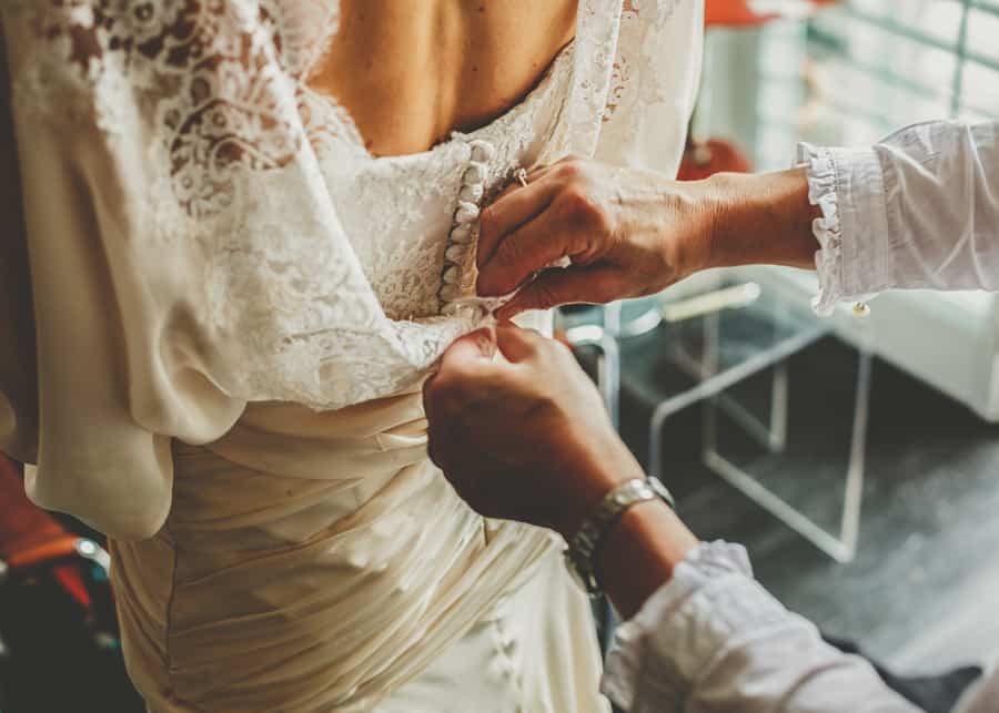 The bride has her dress fastened at the back