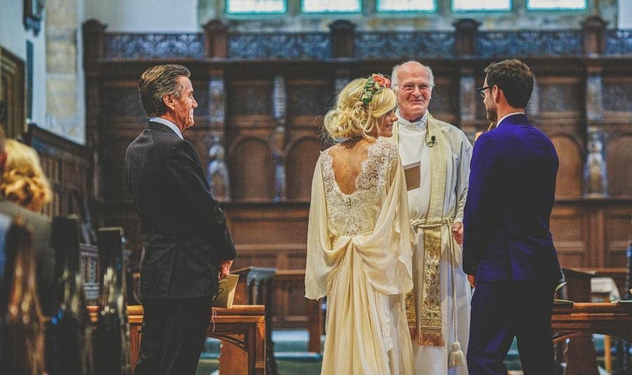 The wedding couple share a joke with the vicar at the Church of St Michael and All Angels, Somerton