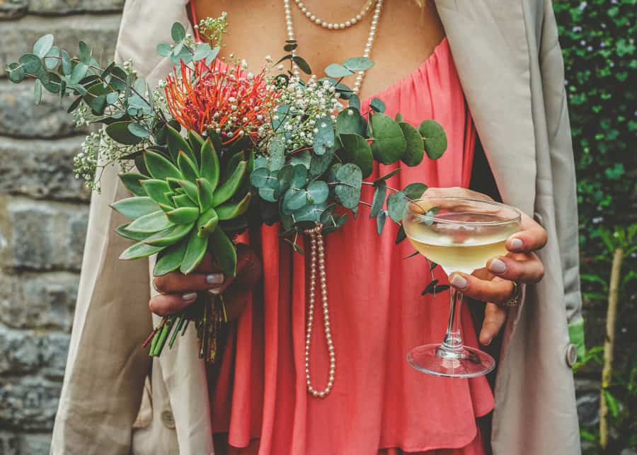 A bridesmaid holds her flowers and a glass of champagne