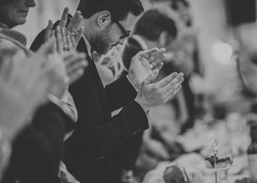 The groom and the rest of the wedding party applaud the best mans speech