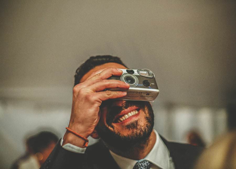 A member of the wedding party holds up a camera