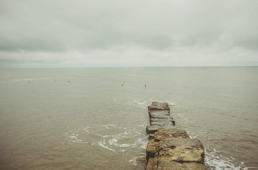 The groom and his ushers swim out to sea on the beach at Lyme Regis in Dorset