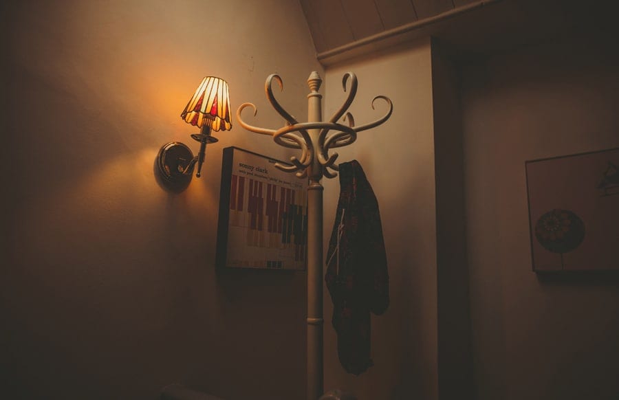 A wooden coat hanger stands next to a wall in the mens apartment