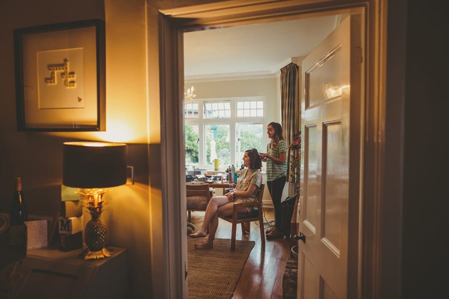 A bridesmaid sits in the back room of her parents house as the hairdresser attends to her hair