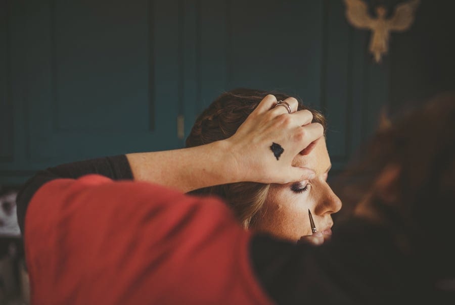 The make up artist applies mascara to the brides eye