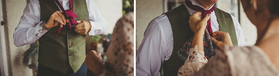 The brides father attempts to fasten his tie and his wife straightens the tie