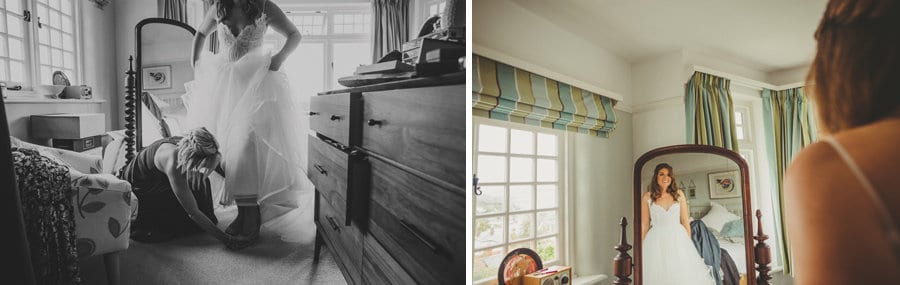 The bride looks in the large mirror as she stands in her parents bedroom