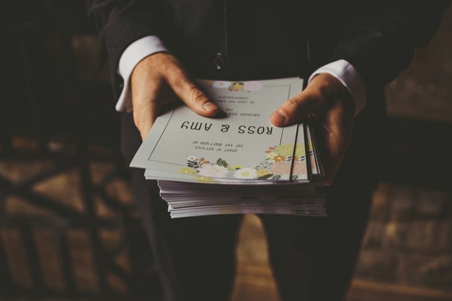 An usher holds the order of service with both hands outside the church