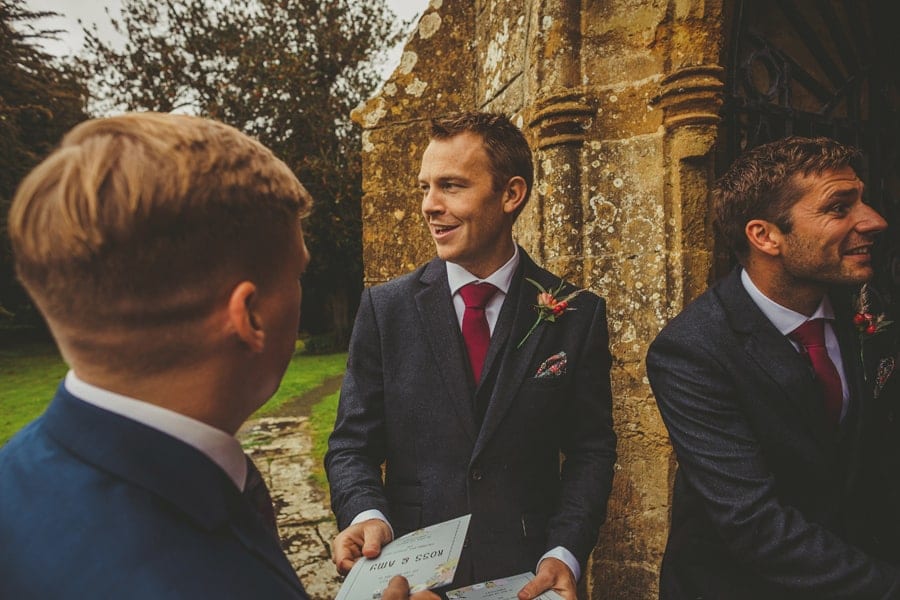 An usher greets wedding guests outside the door of the church and gives them the order of service