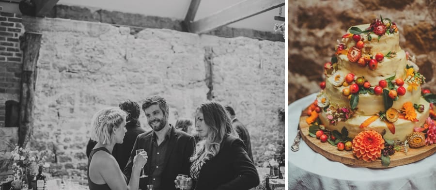Guests talking in the barn and the wedding cake
