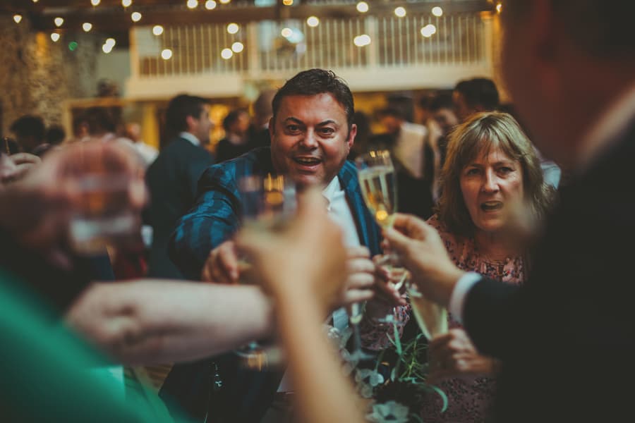 The wedding party put their champagne flutes together and make a toast to the bride and groom