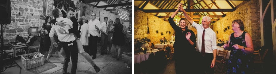A man jumps into another mans arms on the dance floor and the grooms parents dance in the barn