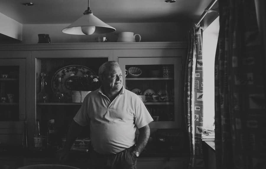 The brides father looks out of the window of the kitchen at Mill farm