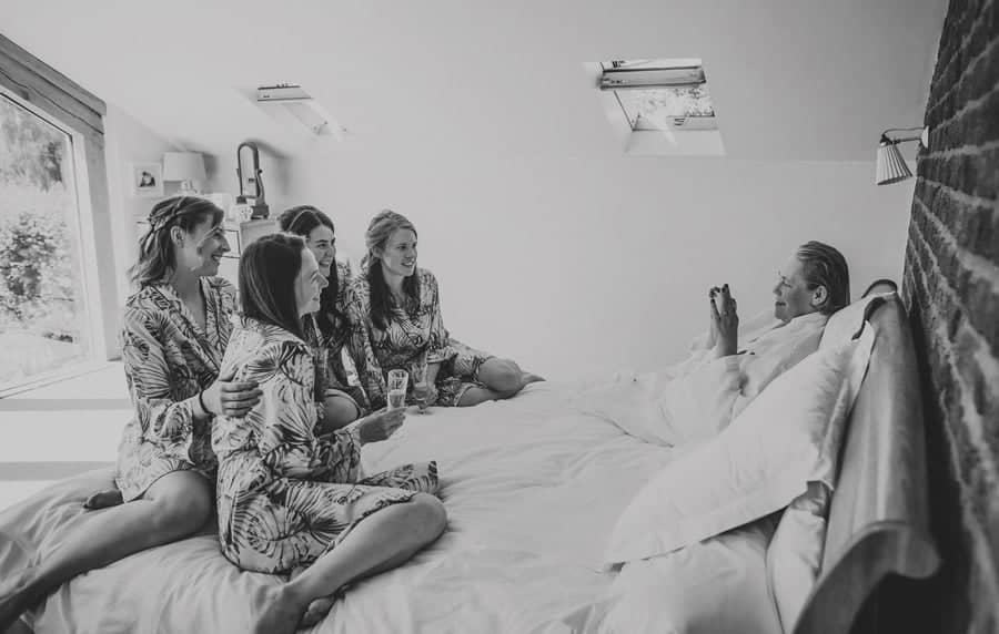 The brides mother takes a photograph of her daughter and her bridesmaids in the bedroom