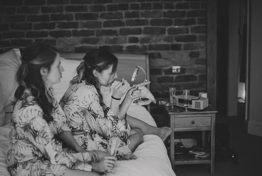 A bridesmaid looks in the mirror sat on the bed