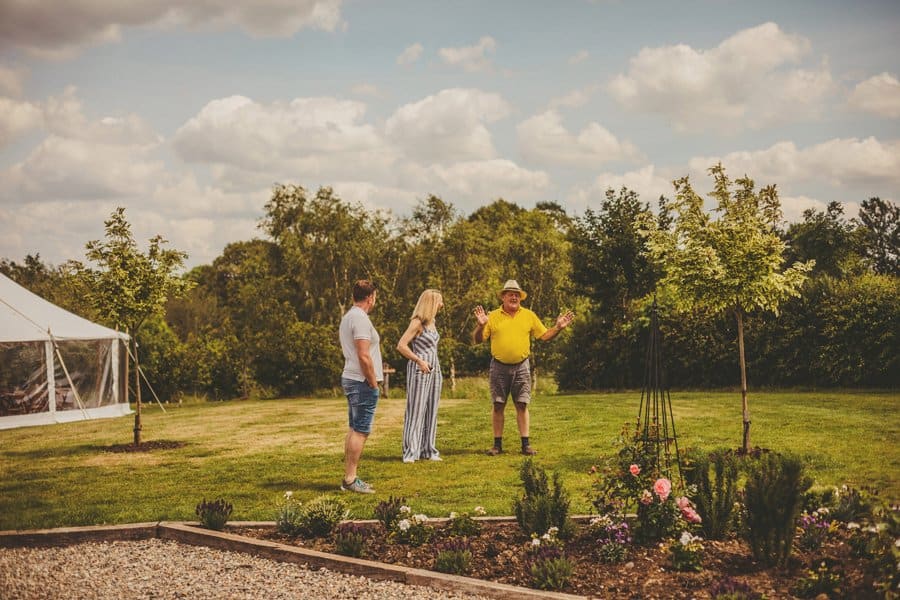 The brides father stands on the lawn at Mill farm and laughs with wedding guests