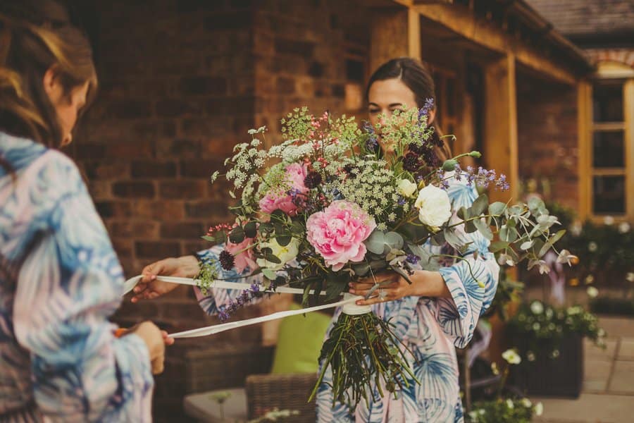 Bridesmaids tying ribbons around the wedding flowers