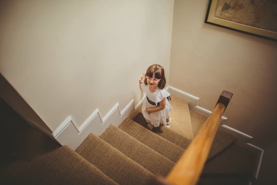 A flowergirl walks up the stairs to watch the bride getting ready