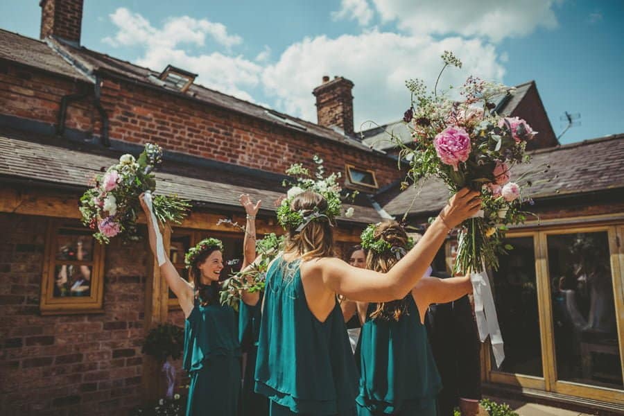 The bridesmaids lift their flowers into the air in the courtyard to celebrate the start of the wedding
