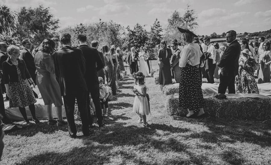 A flowergirl walking down the aisle at the outdoor ceremony