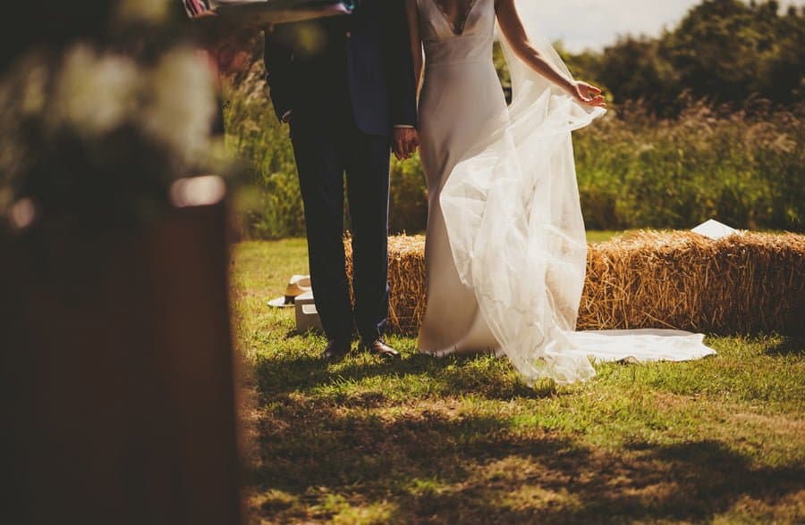 The bride moves her dress to the side during the outdoor ceremony