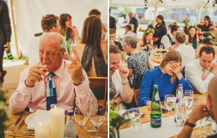 The brides father holds up two fingers and a wedding guests puts her hands to her face and laughs