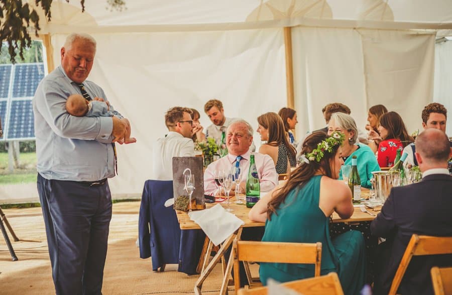 A wedding guest holds a baby boy in the marquee