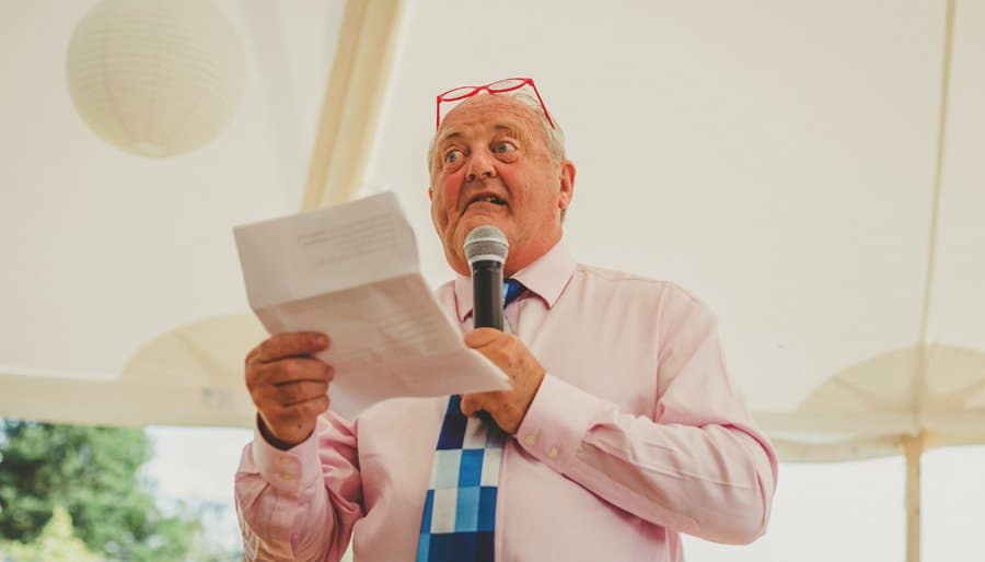 The brides father speaks into a microphone