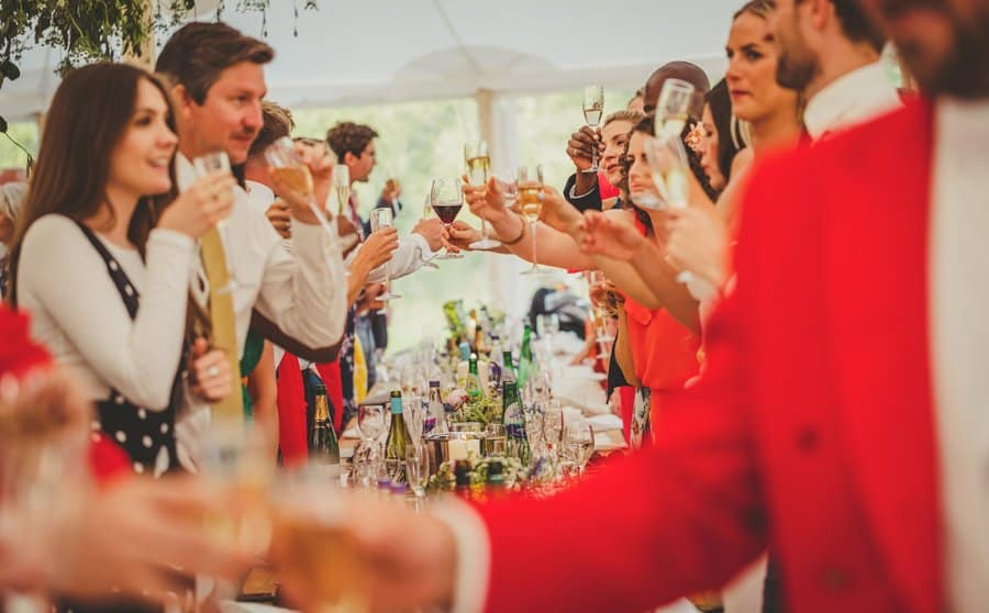 The wedding party celebrate by putting their champagne glasses across the table