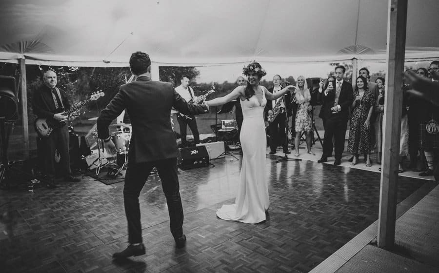 The bride and groom dancing in the marquee as wedding guests look on