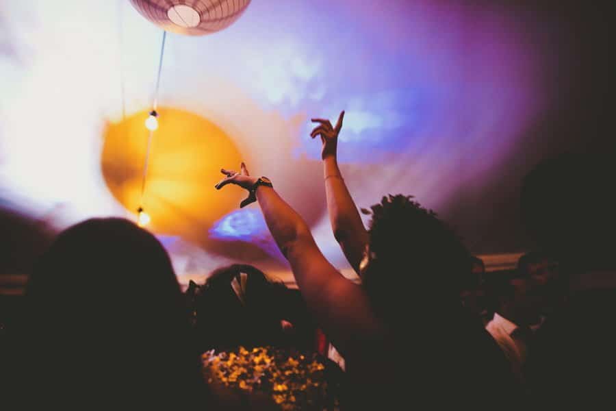 A wedding guest raises her arms into the air and dances in the middle of the marquee