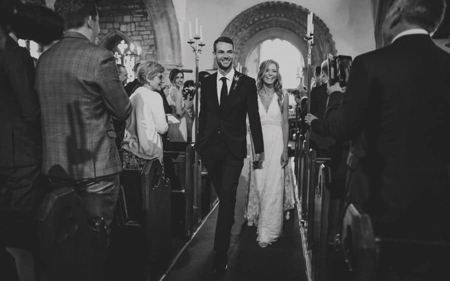 The bride and groom walk down the aisle of the church