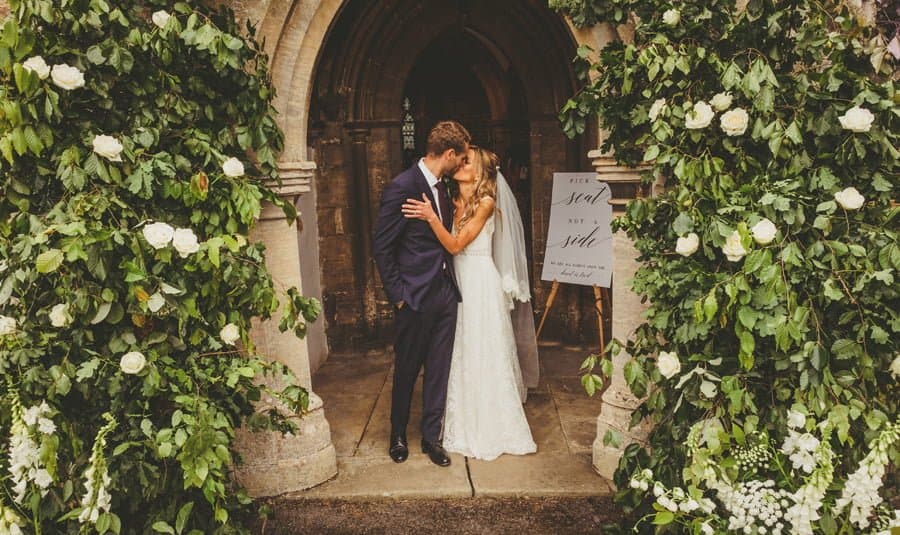 The bride and groom kiss outside the front of the church