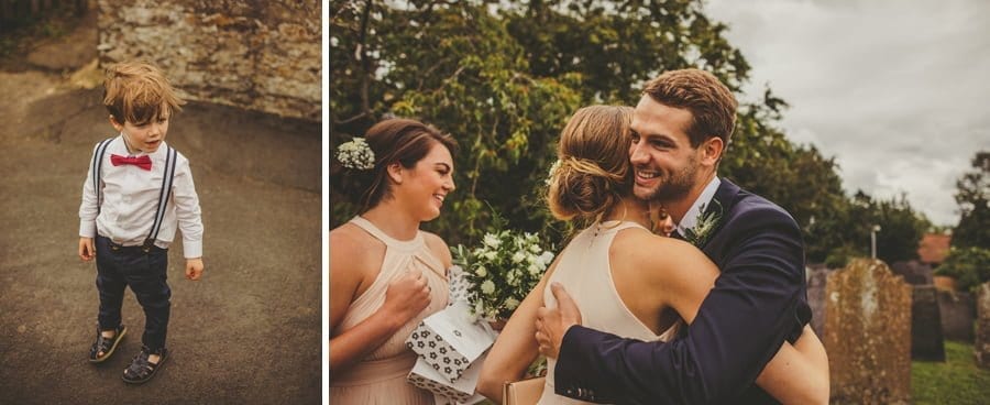 The groom hugs a bridesmaid outside the church and a small boy stands on the path