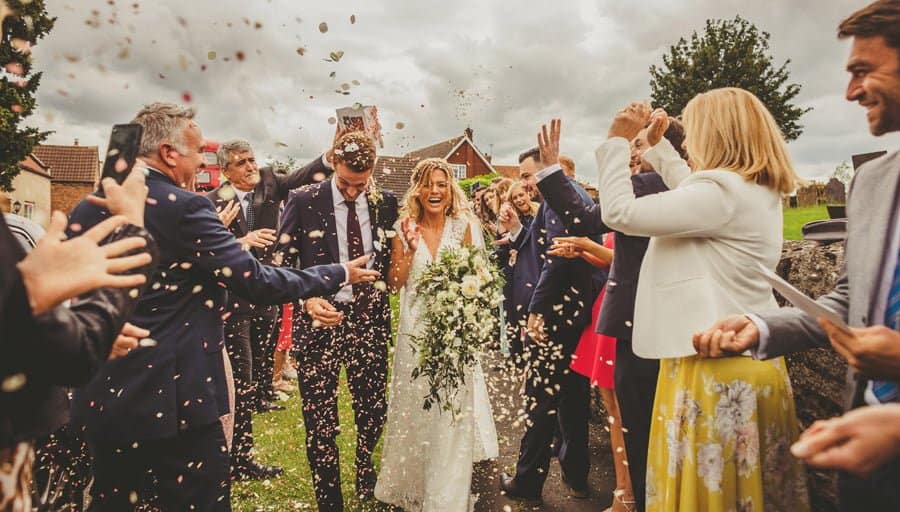 The bride and groom are covered in confetti
