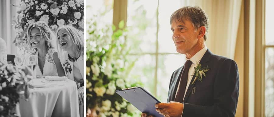 The brides father smiles at the wedding party as he delivers his speech