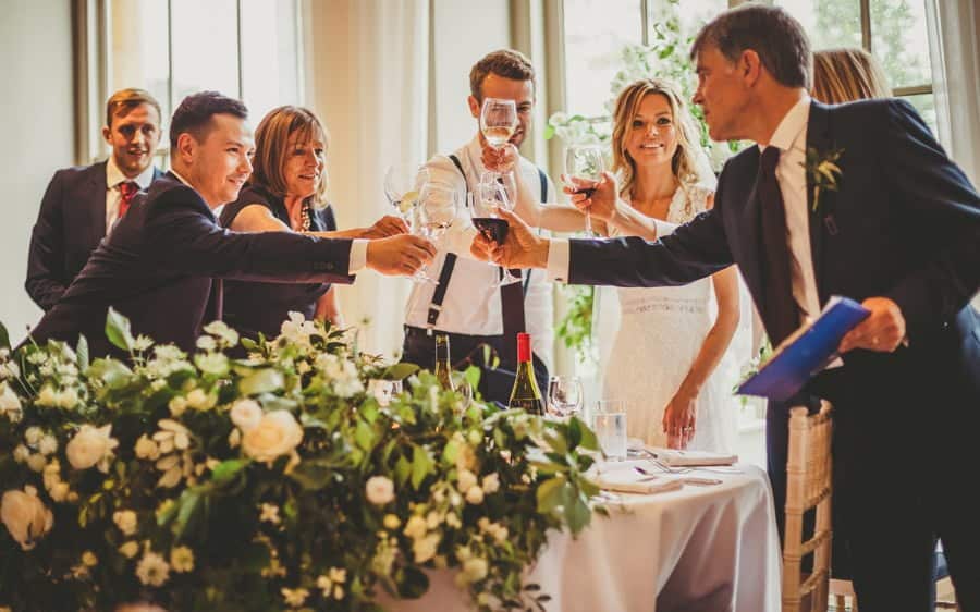 The wedding party hold glasses together and celebrate the brides fathers speech