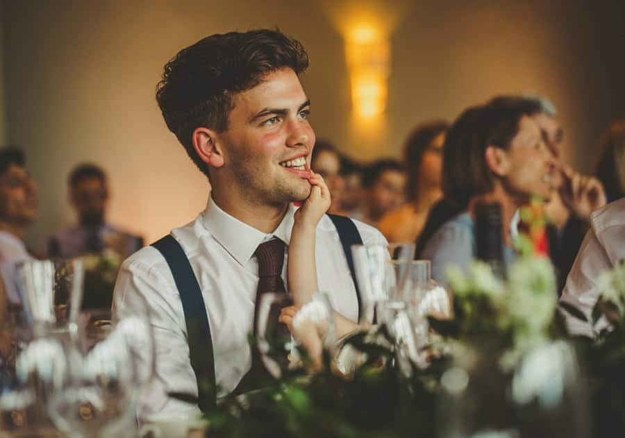 The brides brother smiles as he listens to the grooms speech