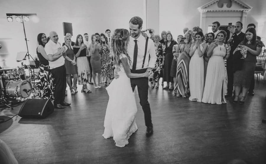 The bride and groom enjoy their first dance together as the wedding party watch at Stubton Hall