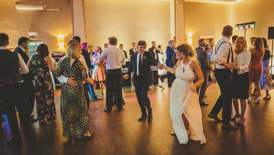 The brides father dances with the brides sister as the wedding band play