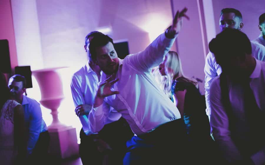 One of the ushers raises his left arm in the air on the dance floor