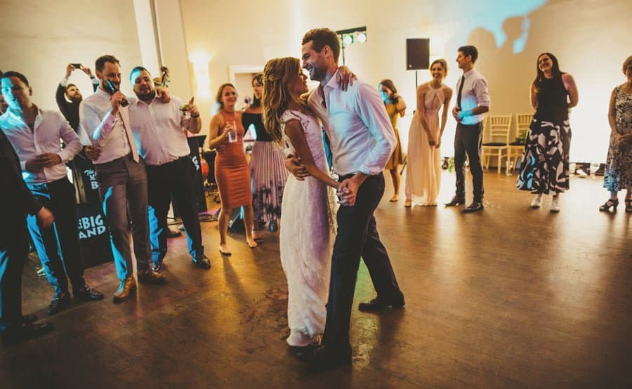 The bride and groom hold hands on the dance floor