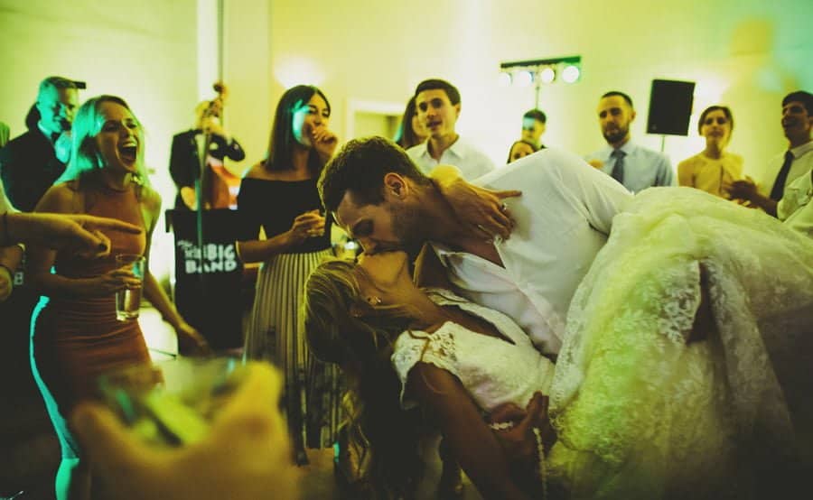 The groom picks up the bride on the dance floor and kisses her