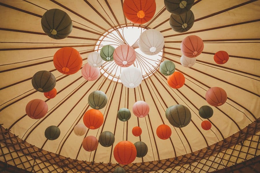 Festive coloured balls hang from the ceiling of the wedding yurt