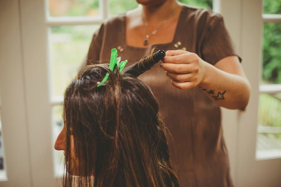 The bride has her hair curled by the hairdresser