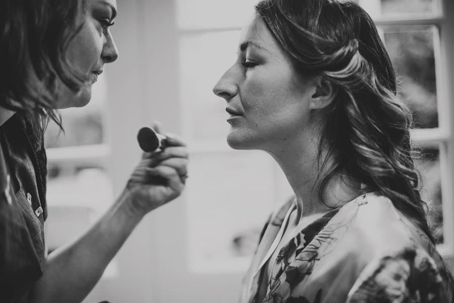 The bride has her mascara applied by the make up artist