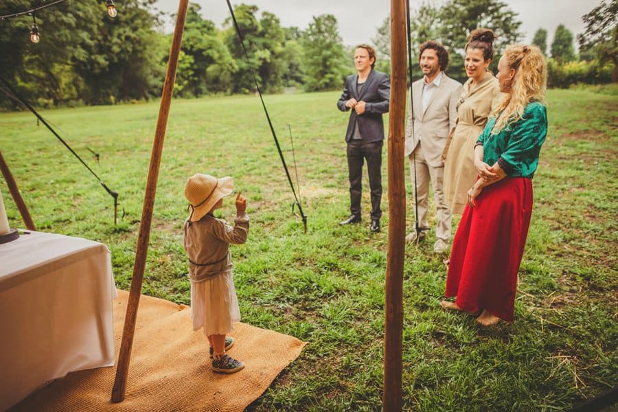 A little girl talks to wedding guests under the canopy